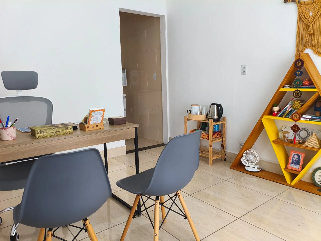 Detalhes da sala de atendimento do Conhece-te com cadeiras e estante de elementos terapêuticos